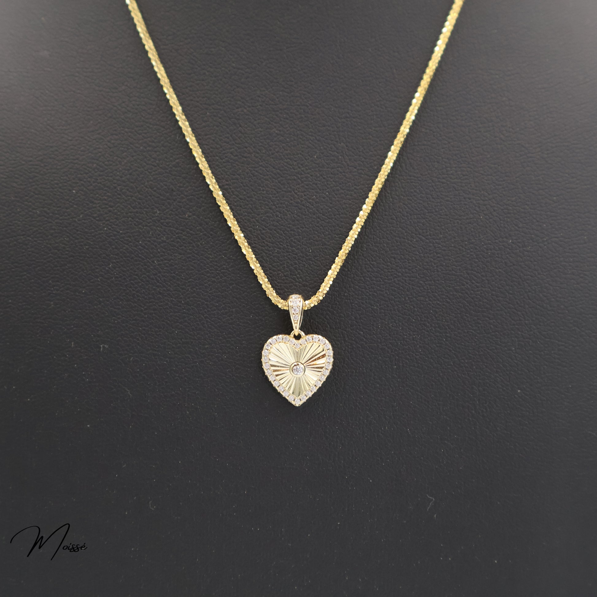 Gold necklace with a heart-shaped pendant on a black background
