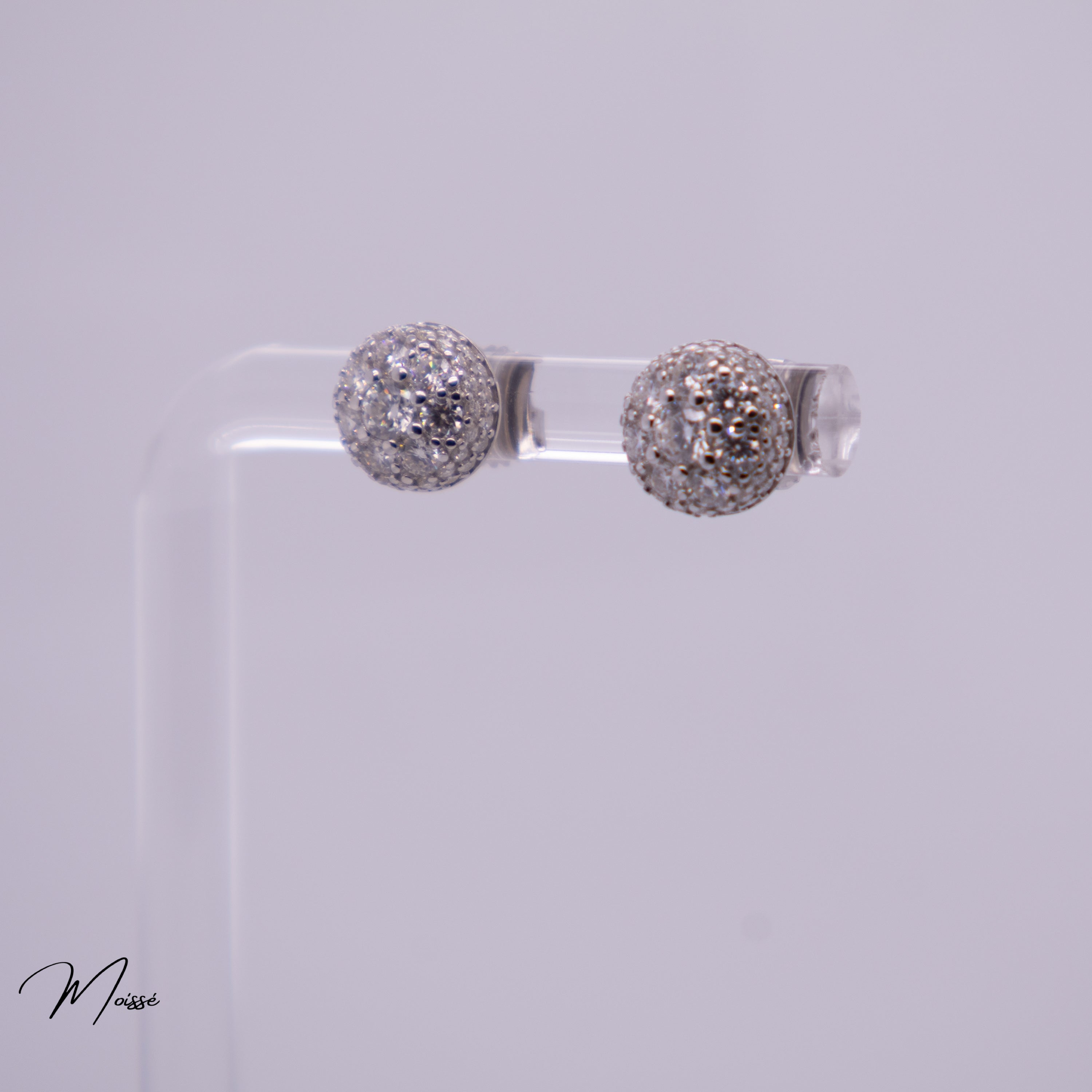Pair of silver ball earrings on a clear stand against a light gray background