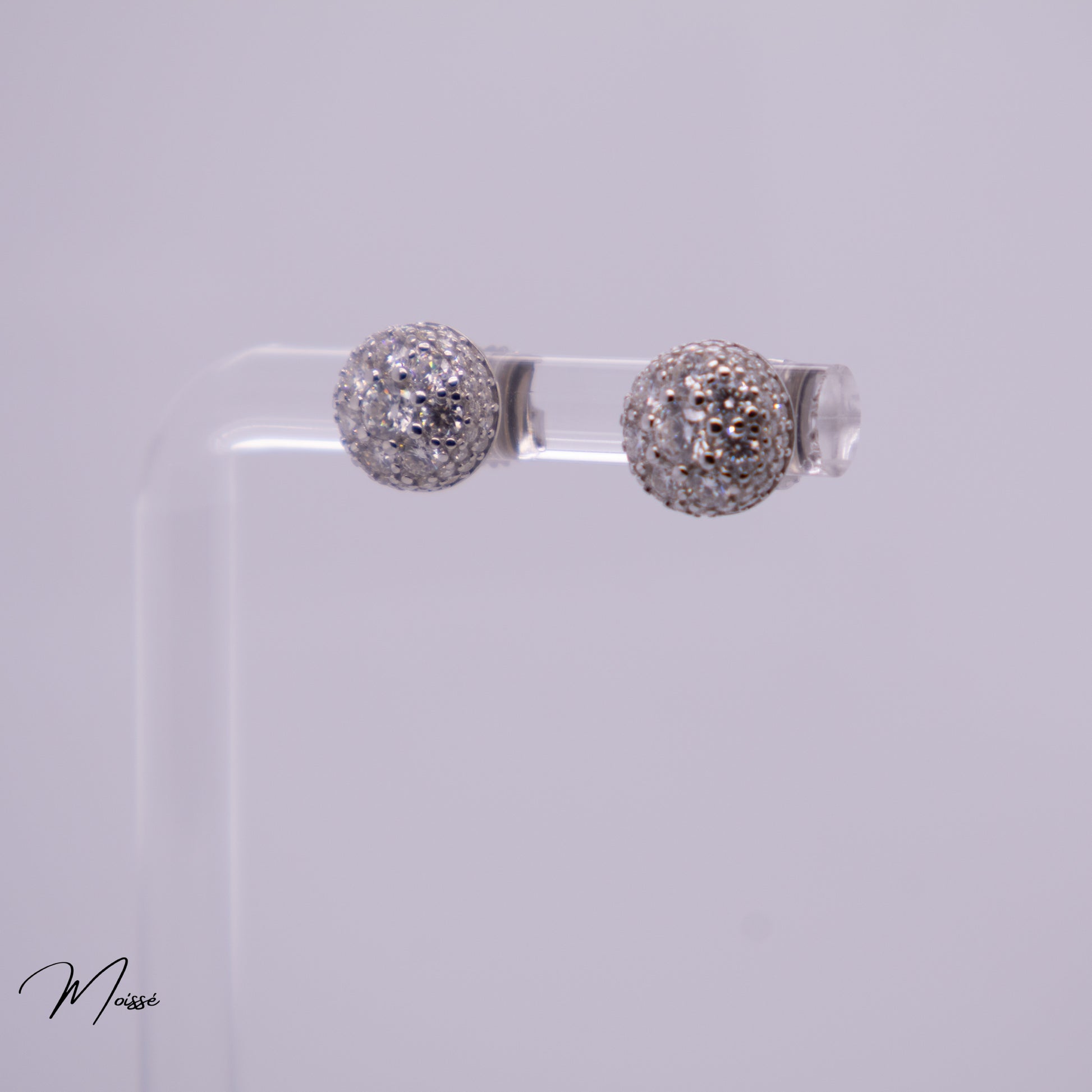 Pair of silver ball earrings on a clear stand against a light gray background