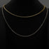 A gold vermeil and a sterling silver tennis necklace on a black display